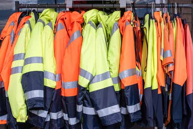 reflective construction clothing hanged together in a room.