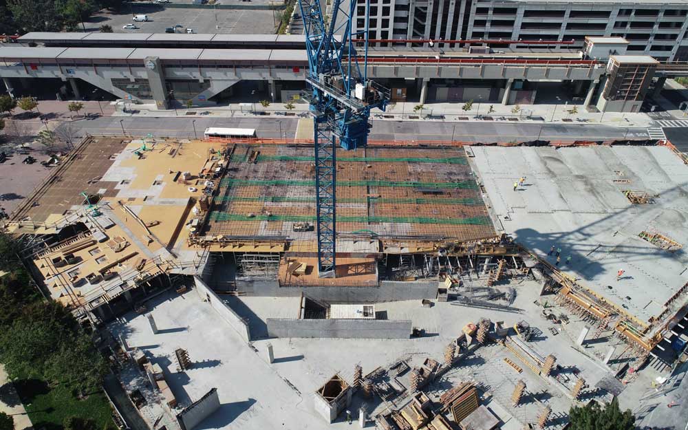 “Areal view of a construction with a large crane in the centre and incomplete construction activity going on