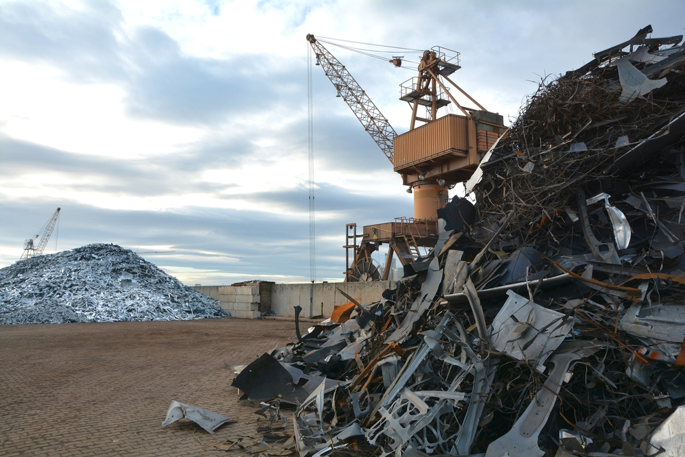 various types of metal scrap ie; ferrous and non ferrous in a yard placed in heaps and cranes to move them